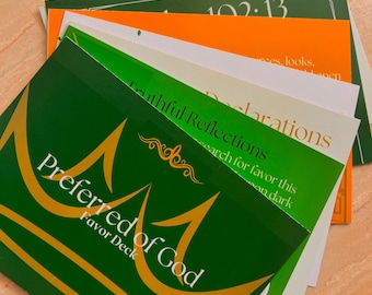 Puede incluir: Un conjunto de tarjetas coloridas, principalmente verdes, naranjas y blancas. La tarjeta superior, verde, muestra la inscripción dorada "Preferred of God" y una corona. Otras tarjetas presentan frases como "Truthful Reflections" y "Declarations".