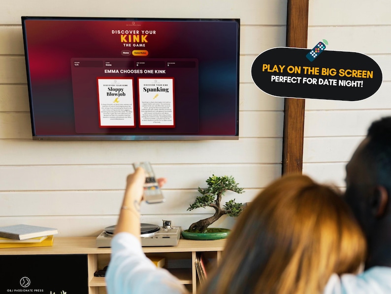 May include: A television screen displays the game Discover Your Kink, featuring a red and black interface with two cards titled Sloppy Blowjob and Spanking. A black speech bubble graphic with yellow and white text reads Play on the big screen.
