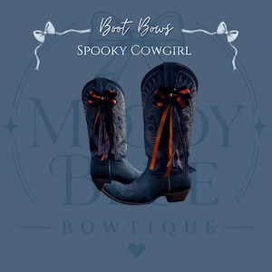 May include: A pair of black leather cowboy boots featuring intricate stitching and decorative bows attached to the shafts. The bows are made of orange and black ribbons with dangling fringe elements. The text Boot Bows SPOOKY COWGIRL is visible.