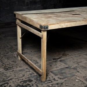 May include: A rustic wooden table with a distressed finish and metal accents. The table has a rectangular top and a simple, sturdy design.