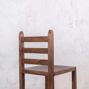 Puede incluir: Silla de madera de color marr&oacute;n oscuro. El respaldo es de listones y el asiento cuadrado. Fabricada en madera, presenta un dise&ntilde;o sencillo y r&uacute;stico. Dimensiones en cent&iacute;metros, ideal para interiores.