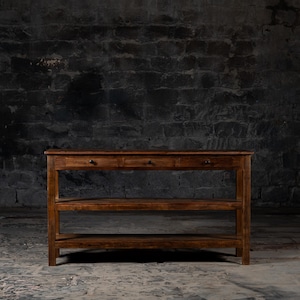 May include: A dark brown wooden console table with three shelves and three drawers. The table has a rustic, farmhouse style.