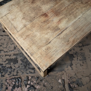 May include: A light wood coffee table with a rectangular top and a black metal frame. The table has a rustic, distressed look.