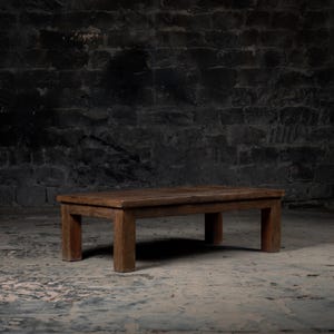 May include: A rustic wooden coffee table with a rectangular top and four legs. The table is made of dark brown wood and has a natural, weathered finish.
