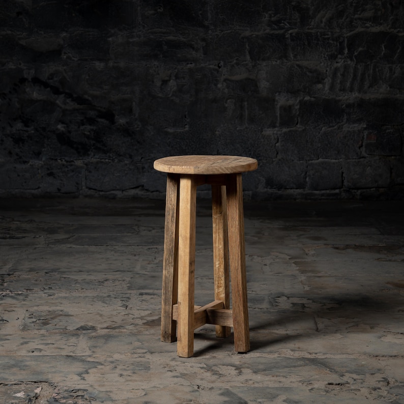 May include: A wooden stool with a round seat and four legs. The stool is made of natural wood and has a rustic look.