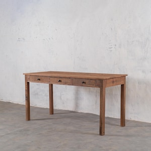 Peut inclure: Un bureau rectangulaire en bois avec trois tiroirs et des boutons noirs. Le bureau est en bois brun clair et a un design simple et rustique. Le bureau mesure environ 152 cm de long, 76 cm de large et 76 cm de haut.