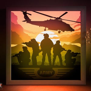 Puede incluir: Obra de arte en silueta enmarcada que representa soldados con rifles, un helicóptero y una puesta de sol. La palabra "ARMY" está en la parte inferior. La obra de arte está en un marco de madera.