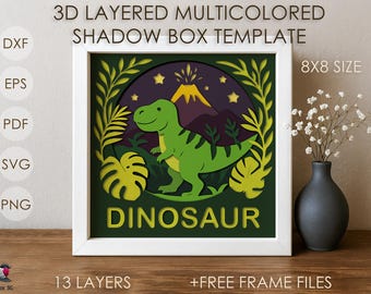 Pode incluir: Modelo de caixa de sombra multicamadas 3D com tema de dinossauro. O design apresenta um dinossauro verde, um vulcão e folhagem, emoldurado em um quadrado branco. O texto "DINOSAUR" é exibido na parte inferior. O tamanho é de 20,32 cm x 20,32 cm.