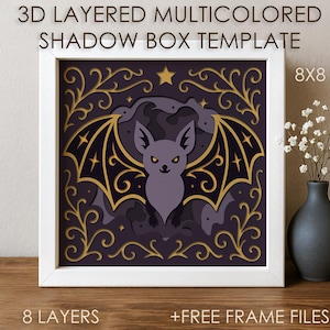 May include: A 3D layered shadow box template in a white frame, featuring a bat design with gold and purple accents. The artwork is 8x8 inches and includes the text "3D LAYERED MULTICOLORED SHADOW BOX TEMPLATE". The image also includes the text "8 LAYERS" and "+FREE FRAME FILES".