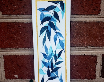 May include: A watercolor painting of blue and teal leaves on a white background with a gold border. The leaves are arranged in a vertical pattern, creating a sense of movement and growth.