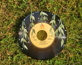 May include: A black vinyl record painted with green leaves and white dots. The record label is yellow with the text "PR 1019" and "HOW LOVE HURTS" in black. The text "THE SYLVERS" is also in black.