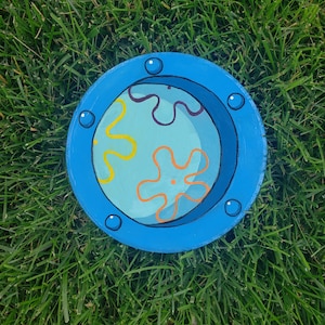 May include: A blue circular dish with a painted design of a yellow and orange flower with a blue background. The dish has a blue rim and five white dots around the rim.