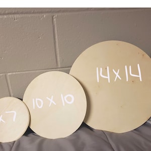 May include: Three round wooden discs of different sizes. The largest disc is 14 inches by 14 inches, the middle disc is 10 inches by 10 inches, and the smallest disc is 7 inches by 7 inches. The discs are all made of light-colored wood and have white writing on them.