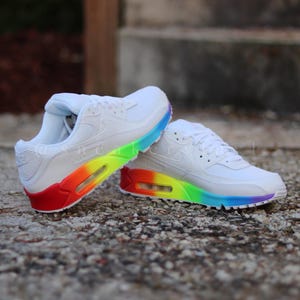 May include: White trainers with a rainbow air sole. The trainers have a white upper and a rainbow coloured air sole.