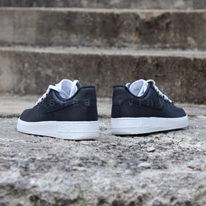 May include: A pair of black leather low-top sneakers with white soles and laces. The sneakers have a Nike logo on the side.