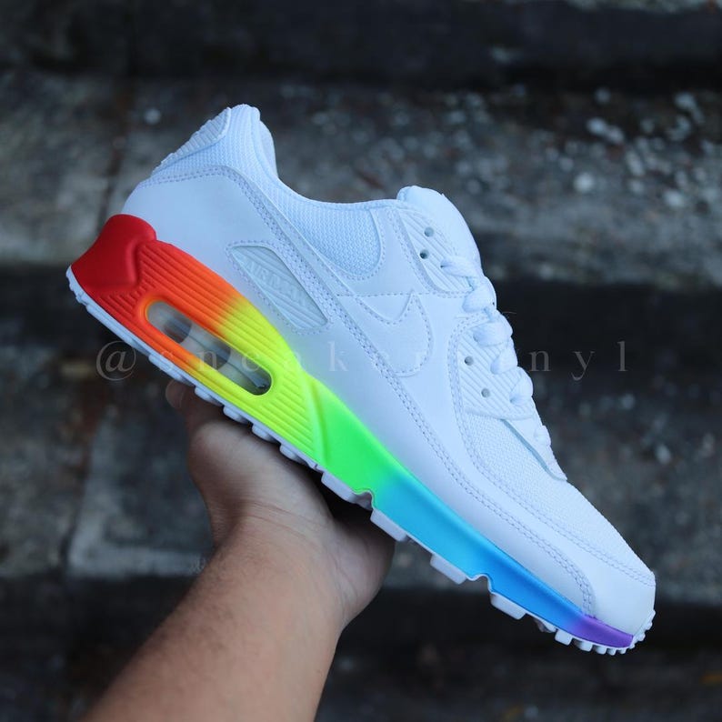 May include: White Nike Air Max 90 trainers with a rainbow gradient on the outsole. The trainers have a white leather upper and a white swoosh logo.