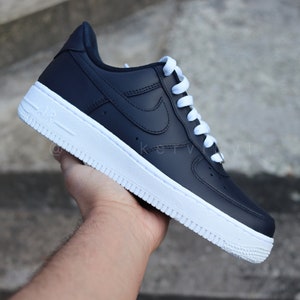 May include: Black leather low-top sneakers with white laces and a white rubber sole.