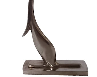 Op de afbeelding: Een zilveren metalen sculptuur van een gestileerd kangoeroe dat op een rechthoekige basis staat.