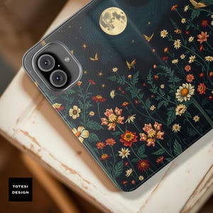 May include: A phone case featuring a floral design with a full moon and stars against a dark blue background. The case has a black border and a camera cutout. The text "TOTESI DESIGN" is in a white box in the lower left corner.