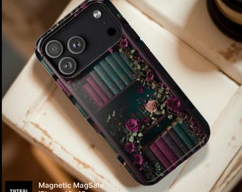 Op de afbeelding: Een zwarte telefoonhoes met een printontwerp van boekenplanken vol met blauwgroene en paarse boeken, geaccentueerd door klimplanten en roze en paarse bloemen. De tekst TOTESI DESIGN, Magnetic MagSafe, iPhone 18-13 en Samsung S26 is zichtbaar.