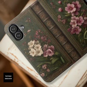 May include: A phone case with a vintage book design. The case features a dark green cover with embossed details and floral illustrations in shades of pink and white. The text "TOTESI DESIGN" is visible.