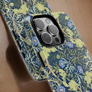 Pu&ograve; includere: Una custodia per telefono nera con un motivo floreale in tonalit&agrave; di blu, verde e giallo. La custodia ha un rialzo per la fotocamera rialzato con un bordo nero.