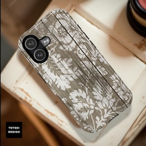 May include: A phone case with a distressed wood grain pattern in shades of gray and white. The case features a floral damask design. The brand name "TOTESI DESIGN" is printed in a black box on the lower left corner.