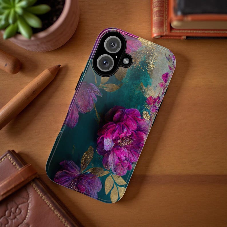 May include: A teal and green phone case with a floral design featuring pink and purple flowers. The case has a clear back and a black camera lens.