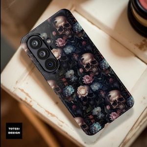 May include: A black smartphone case featuring a repeating pattern of skulls, roses, and other flowers. The skulls are detailed with a realistic appearance, and the flowers are in shades of pink and blue. The case has a glossy finish and the text "TOTESI DESIGN" is visible.