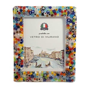 May include: Rectangular photo frame with a colorful mosaic border. The frame's edge is adorned with a vibrant mix of floral and geometric glass pieces in various colors. The frame features a picture of a canal scene and the text "prodotto con VETRO DI MURANO".