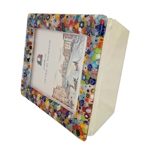 May include: A colorful, rectangular picture frame with a mosaic-like border. The frame features a variety of colors, including blue, red, yellow, and green. The frame holds a picture with a detailed illustration and the text "Vetro di Murano".