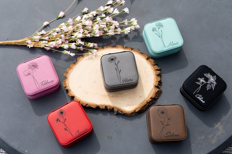 May include: Six small square jewellery boxes with floral designs and personalised names. The boxes are in various colours, including pink, grey, blue, black, red and brown.