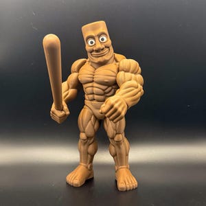 May include: A brown, muscular action figure with a rectangular head and a wide grin, holding a baseball bat. The figure has detailed muscle definition and is posed against a dark background.