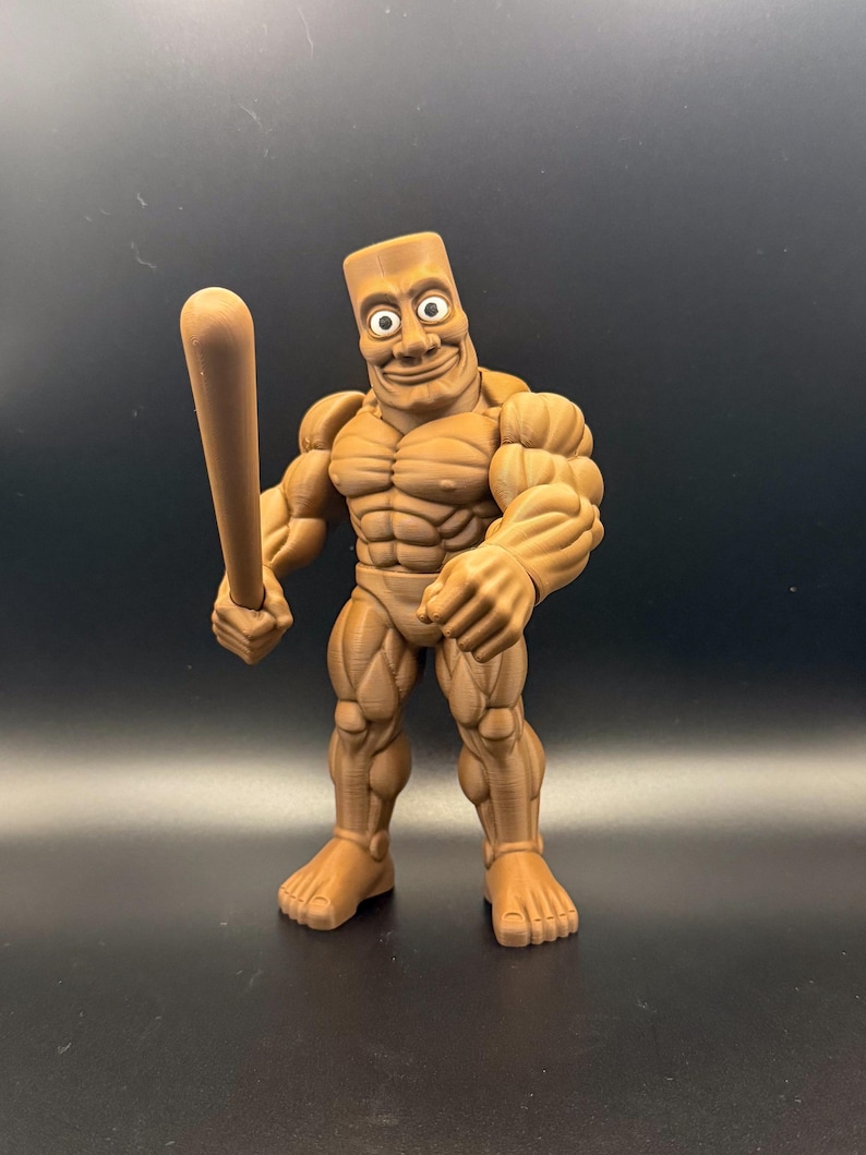 May include: A brown, muscular action figure with a rectangular head and a wide grin, holding a baseball bat. The figure has detailed muscle definition and is posed against a dark background.