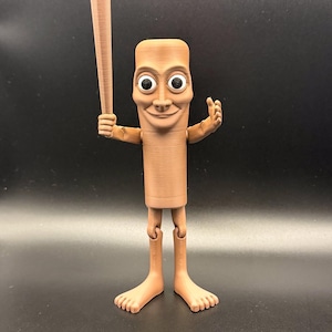 May include: A brown, 3D-printed figurine of a cartoon character holding a baseball bat. The figure has a rectangular body, large eyes, and a smiling face. It has articulated legs and feet, and is posed with one arm raised.