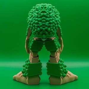 May include: An articulated figure in green and tan, featuring a textured, spherical head and matching leg and foot coverings. The limbs are tan, and the green elements have a textured, organic appearance. The background is a solid green.