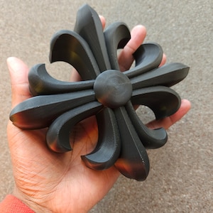 May include: A black 3D printed fleur-de-lis design with a raised center.