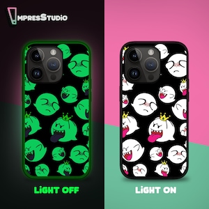 Pode incluir: Uma capa de telefone preta com um design que brilha no escuro. A capa apresenta um padrão de fantasmas brancos com olhos e bocas pretos, e fantasmas verdes com olhos e bocas pretos. O texto "LIGHT OFF" e "LIGHT ON" está impresso abaixo das capas.