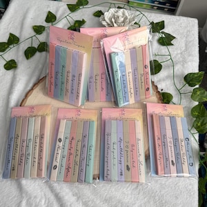 Puede incluir: Se muestran varios paquetes de pestañas de libros Ink & Edge en colores pastel. Cada pestaña está etiquetada con texto como "Enemies to Lovers" y "Happily Ever After". Las pestañas están empaquetadas en plástico transparente y dispuestas sobre una superficie blanca.