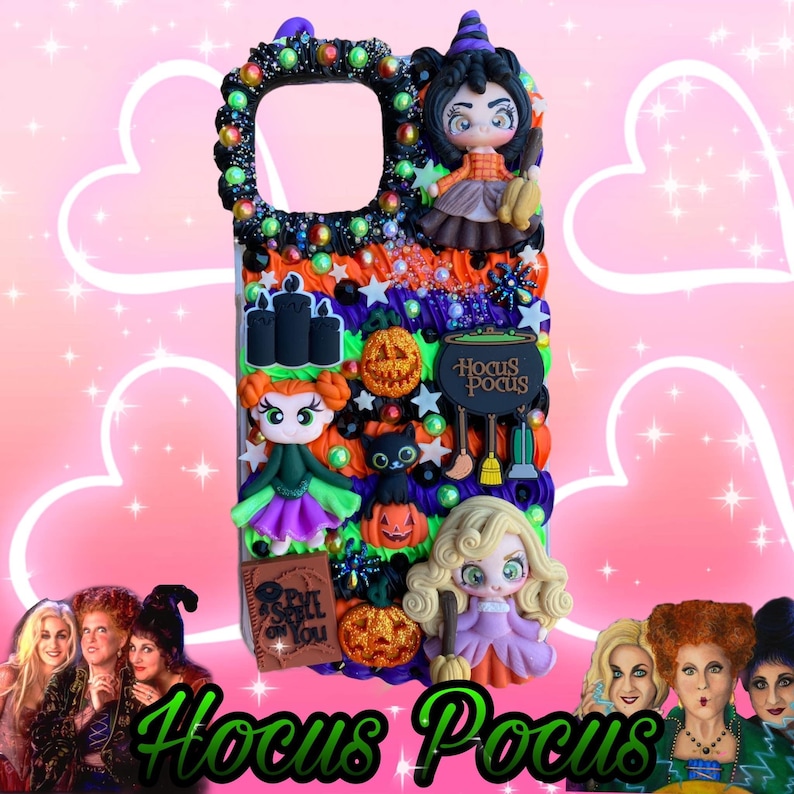 May include: A decorative phone case featuring a Halloween theme with the text "Hocus Pocus". The case is adorned with miniature witch figures, pumpkins, a black cat, and the words "Hocus Pocus". The case is decorated with colorful beads and embellishments.