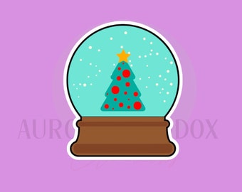 May include: A snow globe with a green Christmas tree with red polka dots and a yellow star on top. The snow globe is filled with white snow.