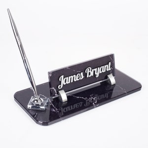 May include: Black marble desk organiser with a silver pen holder and a nameplate that reads "James Bryant".