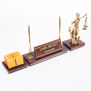 May include: A mahogany desk organiser with a gold pen holder, a brass statue of Lady Justice, and a nameplate that reads "JAMES BRYANT MANAGER".