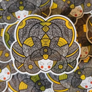 May include: A sticker featuring a detailed illustration of a stylized face with a patterned hair design. The face is surrounded by a black and white pattern with yellow accents. The sticker is a circular shape.