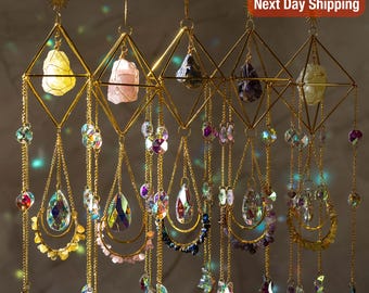 Può includere: Acchiappasole geometrici color oro con cristalli e pietre preziose sospese. Ogni acchiappasole presenta una cornice a forma di diamante che contiene una pietra preziosa di colore diverso. Sotto, pendono pendenti di cristallo a goccia e perline più piccole.