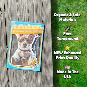 Puede incluir: Un ambientador de coche blanco y azul con un perro de dibujos animados que lleva gafas de sol y un collar rojo. El embalaje tiene el texto "The Freshener" y "The Best Car Fresheners in the World!" y el texto "OMG!" en un bocadillo.