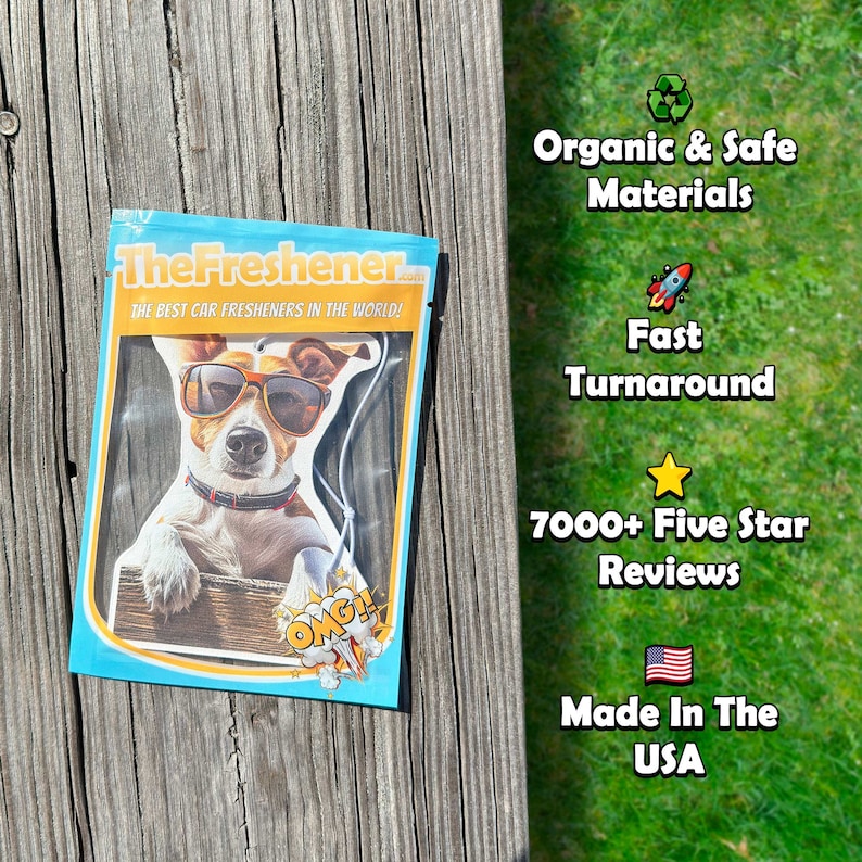 K&ouml;nnte beinhalten: Eine wei&szlig;e Verpackung mit blauem Rand, auf der ein Cartoon-Hund mit Sonnenbrille und rotem Halsband zu sehen ist. Die Verpackung tr&auml;gt den Schriftzug "TheFreshener.com" und "The best car fresheners in the world!" Die Verpackung liegt auf einer Holzoberfl&auml;che.