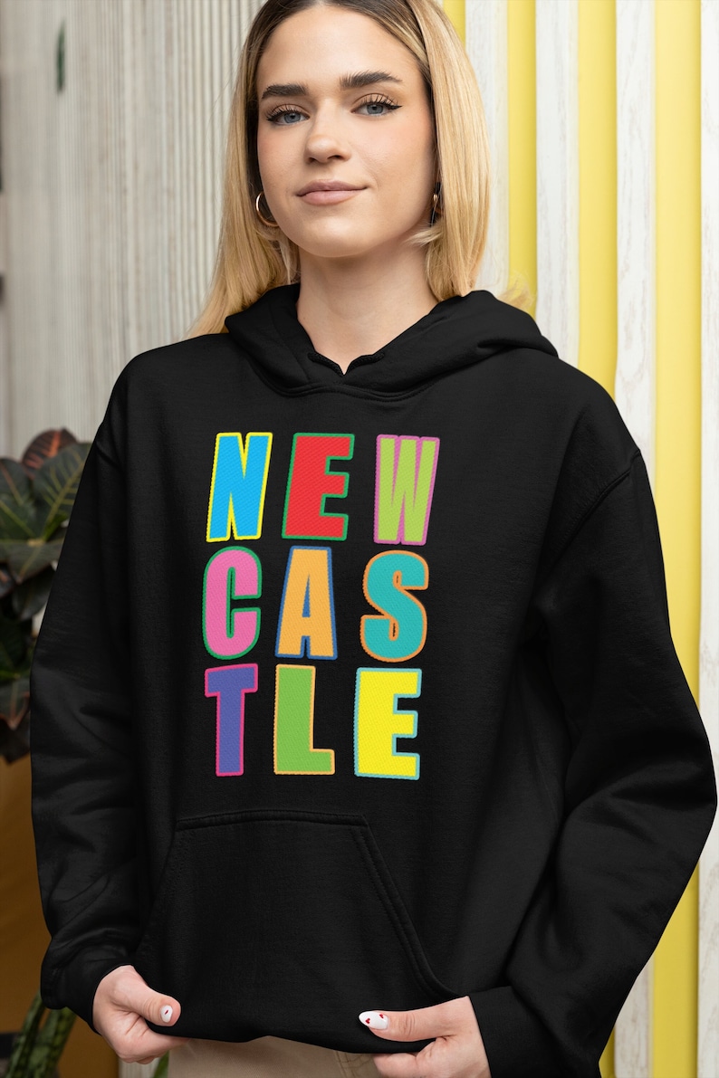 May include: Black hooded sweatshirt with a colourful "NEWCASTLE" graphic printed on the front.
