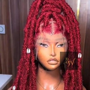 May include: A burgundy-colored wig with long, textured locs. The wig features a lace front and is adorned with white shell accents. A gold necklace with a butterfly pendant is visible.