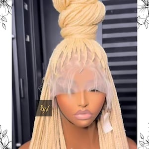 May include: A blonde braided wig styled with long braids and a bun on top. The wig features a lace front and is worn on a mannequin head. The wig has a natural look and is a light, golden color.